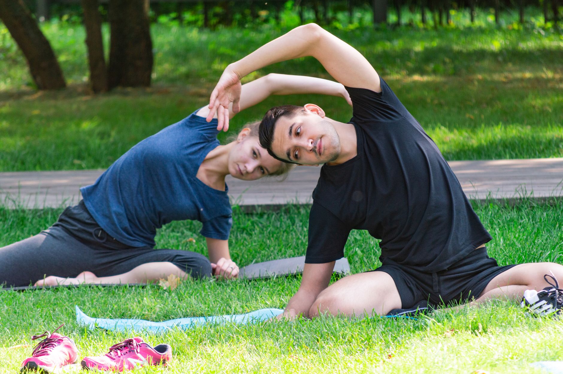 A couple doing yoga exercises outdoors on green grass in a park. — Are You Making These CBD Shops Products Blunders